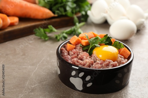 Natural pet food in feeding bowl on grey table, closeup. Space for text