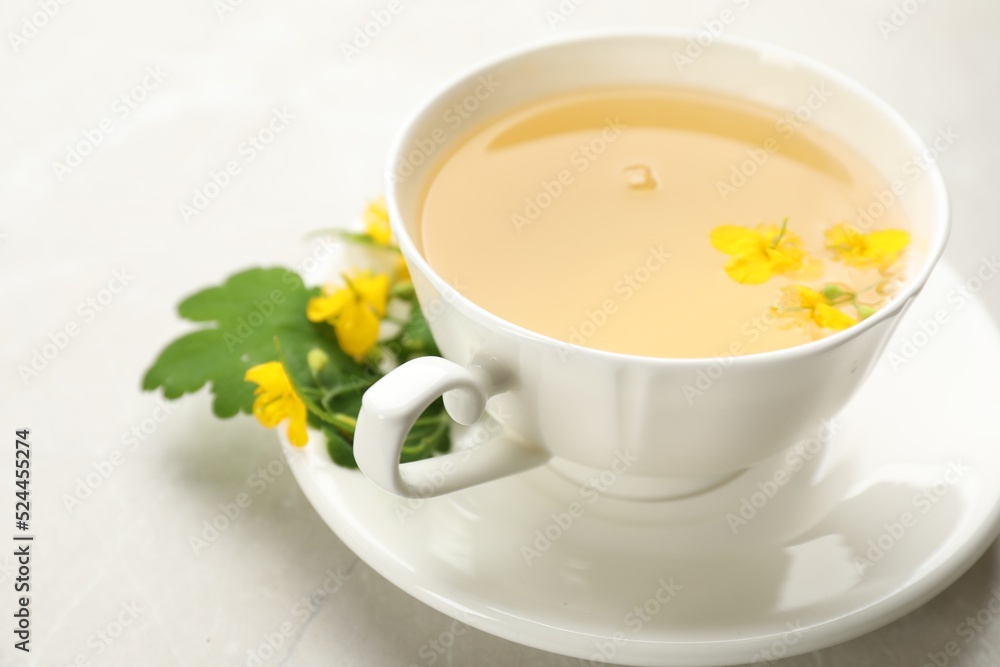 Cup of aromatic celandine tea and flowers on grey table, closeup Cup of aromatic celandine tea and flowers on grey table, closeup