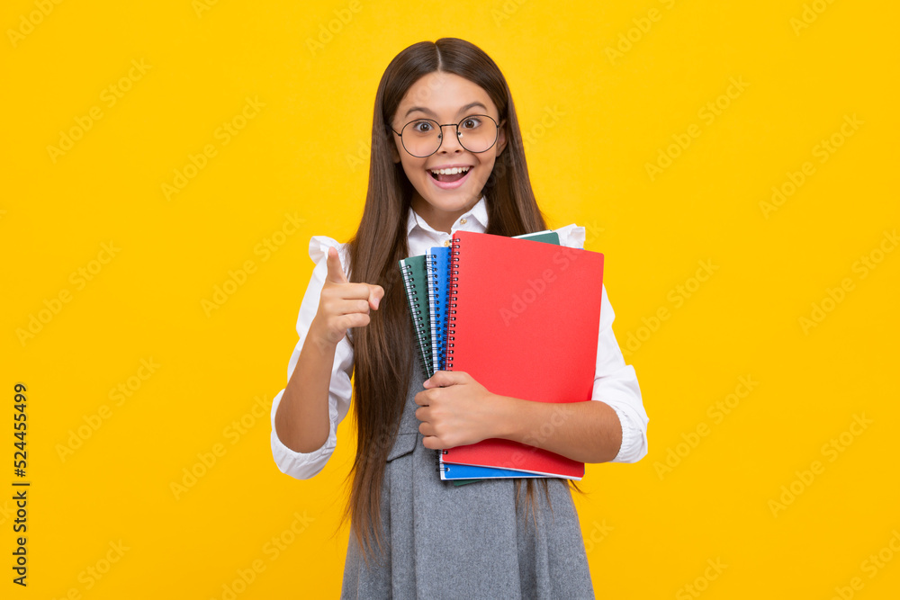 Back to school. Teenager schoolgirl with book ready to learn. School girl children on isolated yellow studio background. Excited face, cheerful emotions of teenager girl. Back to school. Teenager schoolgirl with book ready to learn. School girl children on isolated yellow studio background. Excited face, cheerful emotions of teenager girl.