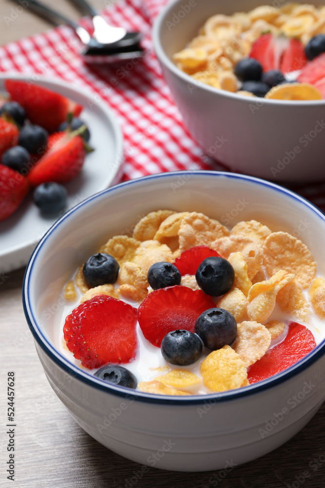 Delicious crispy cornflakes with milk and fresh berries on wooden table, closeup Delicious crispy cornflakes with milk and fresh berries on wooden table, closeup