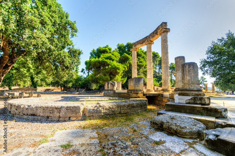 Ruins of the ancient site of Olympia, in Greece where the Olympic games originate from. View of the archaeological site with Ionic pillars on a summer day.