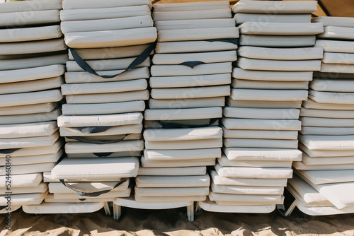 stack of white sunbeds at a beach, closeup