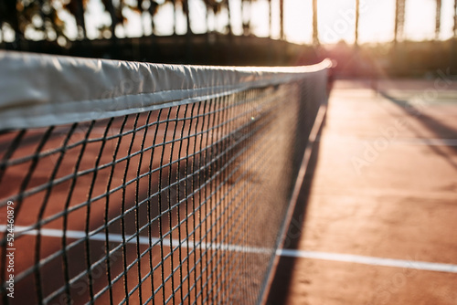 Closeup of a net on a tennis court in sunrise sun light, outdoors.