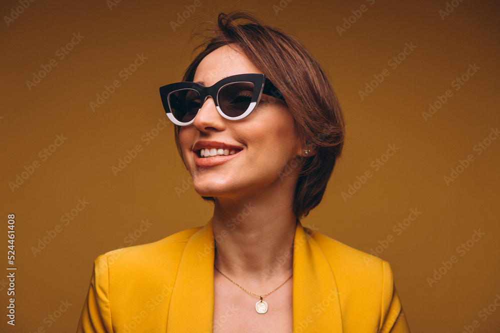 Portrait of woman in yellow suit wearing black and white sunglasses isolated in studio Portrait of woman in yellow suit wearing black and white sunglasses isolated in studio