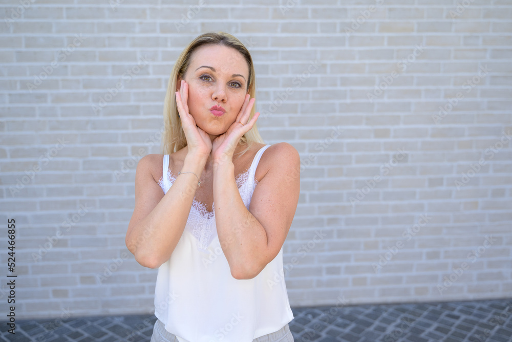Simpering blond woman pursing her lips for the camera Simpering blond woman pursing her lips for the camera