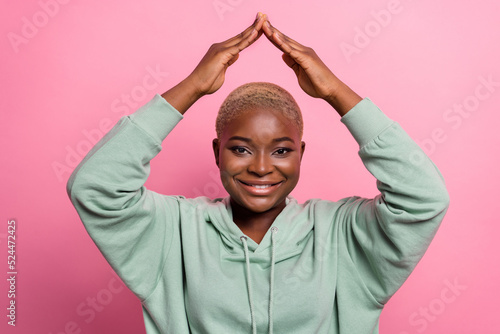 Portrait of attractive good mood lady move to new home apartment hold hands above her head isolated on pink color background © deagreez