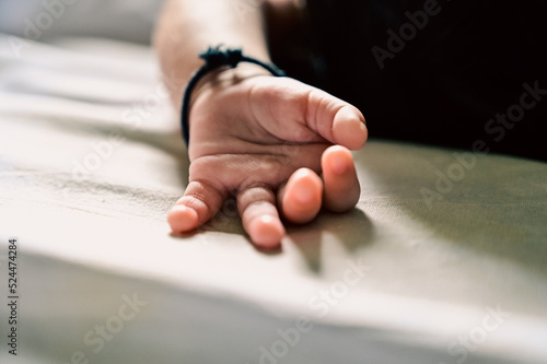 Small Baby hand fingers. Lovely Baby hand with black thread as blessing god protection. Indian Newborn baby. White Cloth 