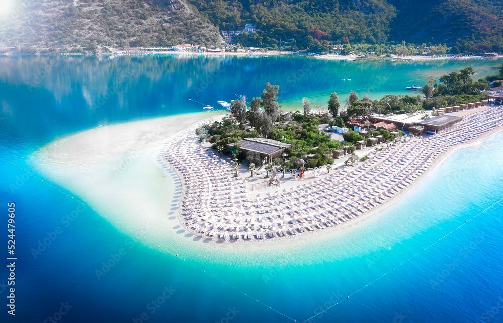 Summer landscape aerial view of turqurose lagoon with white sand and straw umbrallas. Top view of the bottom near the shore. Touristic place Oludeniz near Fethiye.