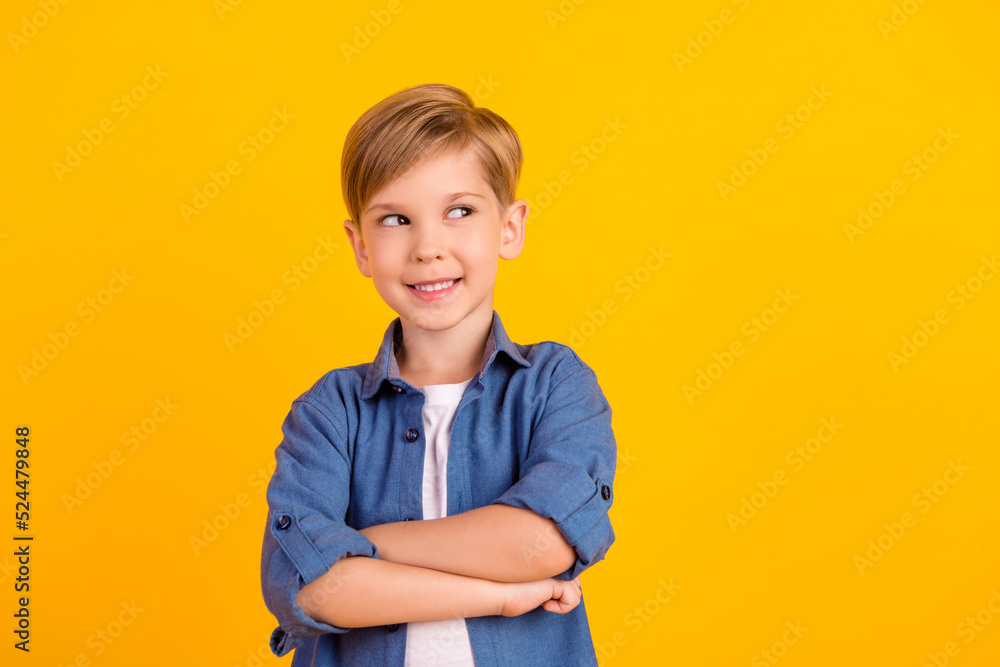 Photo of smart creative minded boy folded arms toothy smile look empty space isolated on yellow color background Photo of smart creative minded boy folded arms toothy smile look empty space isolated on yellow color background