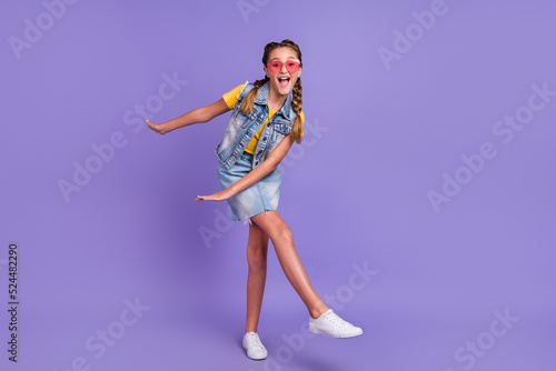 Full body photo of cool school blond girl dance wear eyewear t-shirt jeans vest skirt boots isolated on violet background © deagreez
