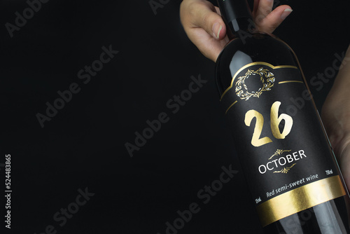 October 26th. Day 26 of month, Calendar date. Hands hold bottle of red wine with a calendar date on label. Autumn month, day of the year concept.