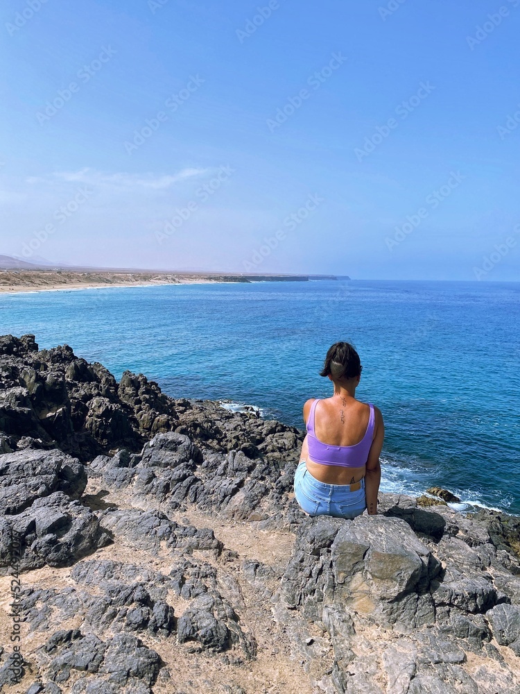 Young woman observing a beautiful paradisiacal landscape on the island of Fuerteventura