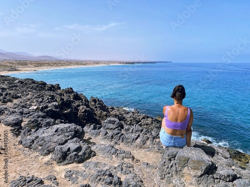 Young woman observing a beautiful paradisiacal landscape on the island of Fuerteventura