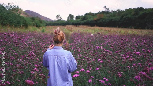 Asian woman is wearing face mask in a flower meadow outdoor for freedom in pandemic concept.