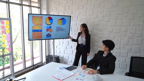 Business woman is explaining financial report on display screen in a meeting.