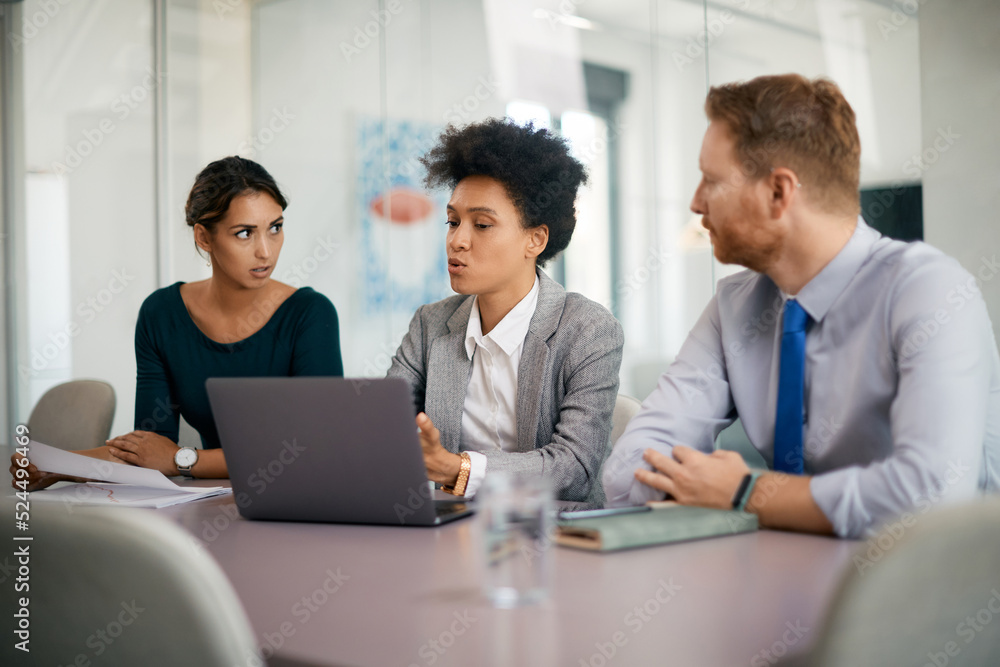 Black female executive and her business team using laptop during meeting in office. Black female executive and her business team using laptop during meeting in office.