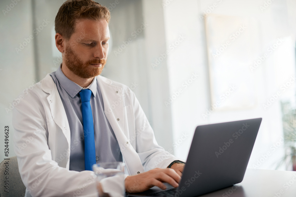 General practitioner using laptop while working at doctor's office. General practitioner using laptop while working at doctor's office.