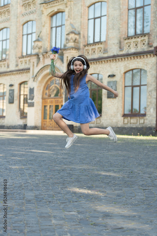 amazed teen girl in headphones. girl jump outdoor. carefree girl jumping feel happiness