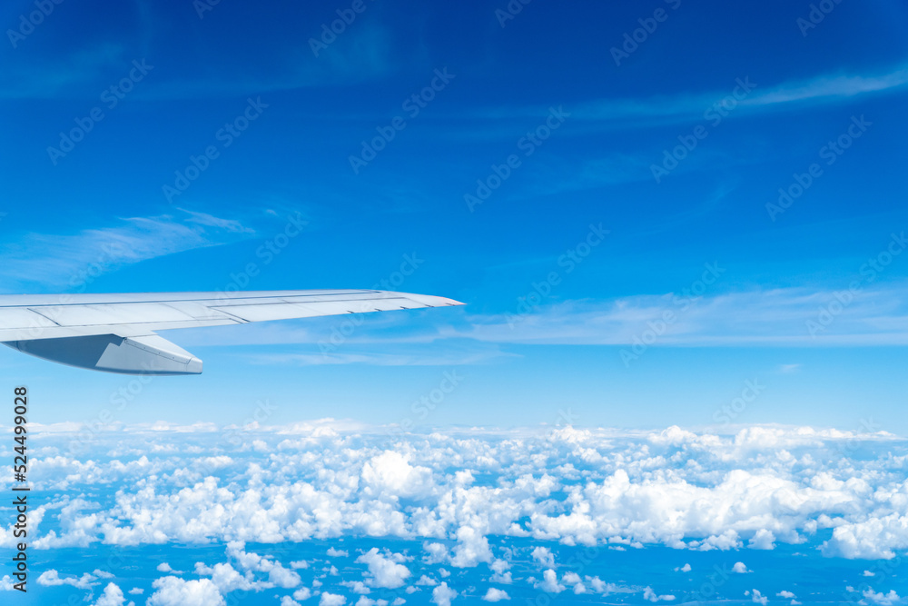 The wing of an airplane against the background of a cloudy sky in flight in the summer.
