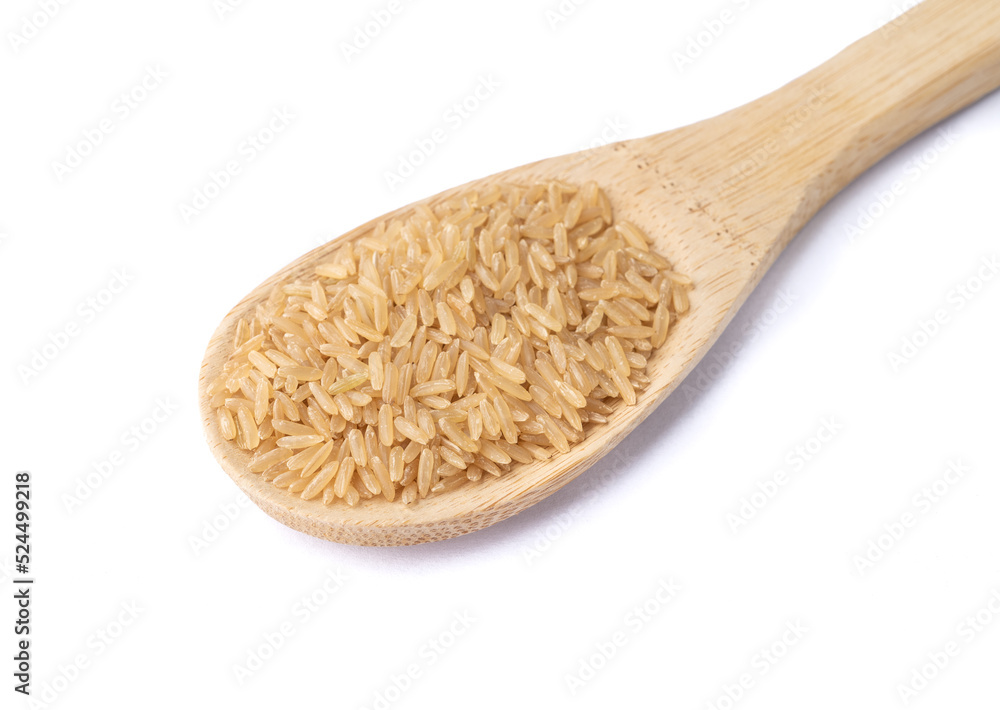 Raw brown whole rice in a spoon isolated over white background Raw brown whole rice in a spoon isolated over white background