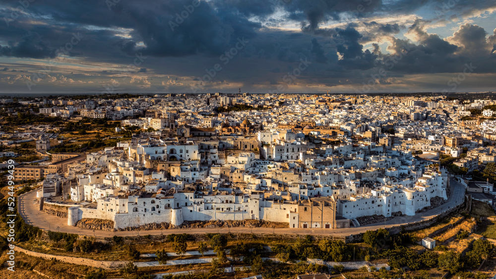 Overview of Ostuni (BR), the white city perched on the hill, with the typical white houses. Aerial photo with the drone of June 2022 photo taken at dawn.