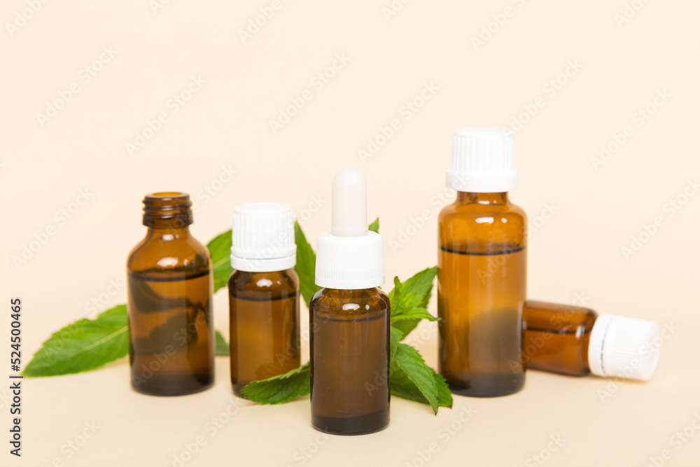 Natural Mint Essential Oil in a Glass Bottle. organic cosmetics with herbal extracts of mint on colored background Natural Mint Essential Oil in a Glass Bottle. organic cosmetics with herbal extracts of mint on colored background