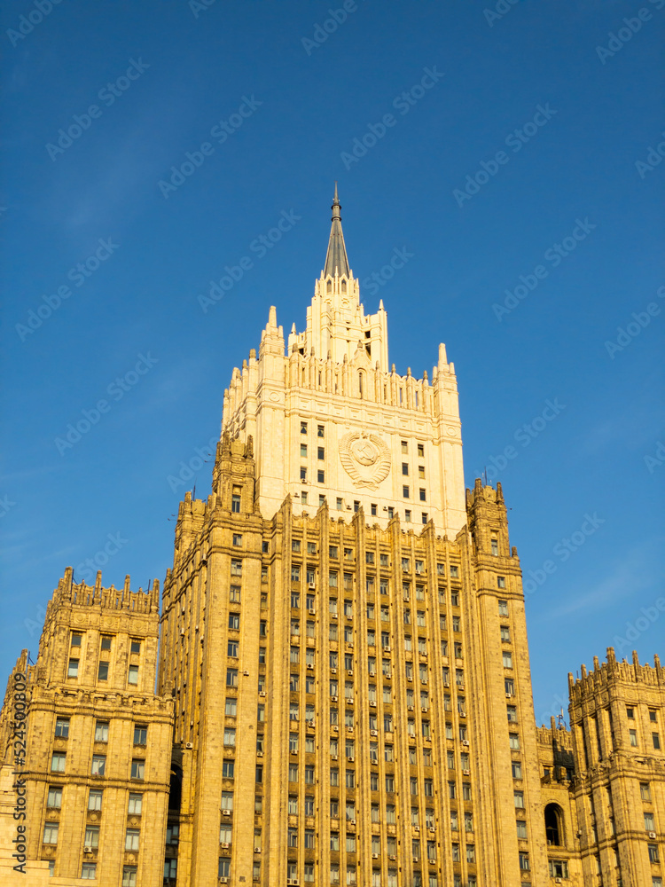 Obraz premium Moscow cityscape within day time. Offices buildings exterior. Building of the Ministry of Foreign Affairs MFA. Rooftops of residential houses on blue sky, bottom up view coat of arms of the USSR