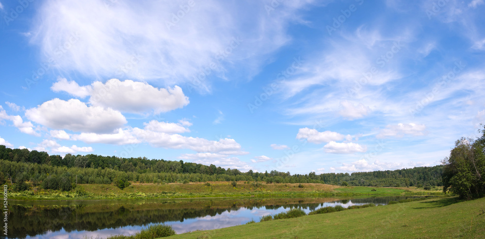 Rural river among the greenery of summer. Summer river in greenery outdoors. Rural river in summertime. Summer river landscape