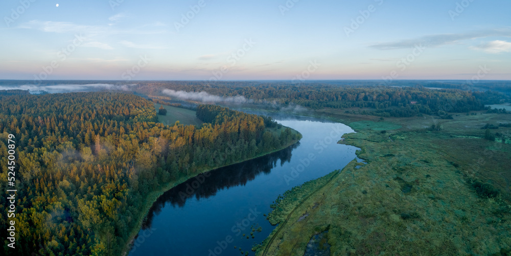 Summer dawn over foggy forest and river aerial drone view. Aerial panoramic landscape with sunset over the river and beautiful sky.