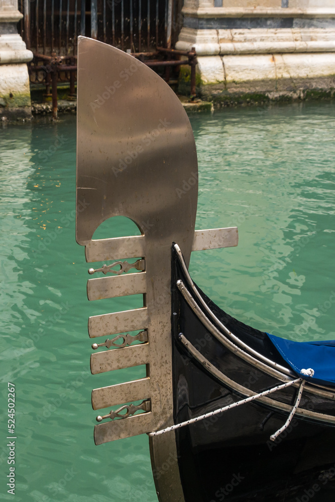 Bow of a gondola in a canal at Venice, Veneto, Italy.