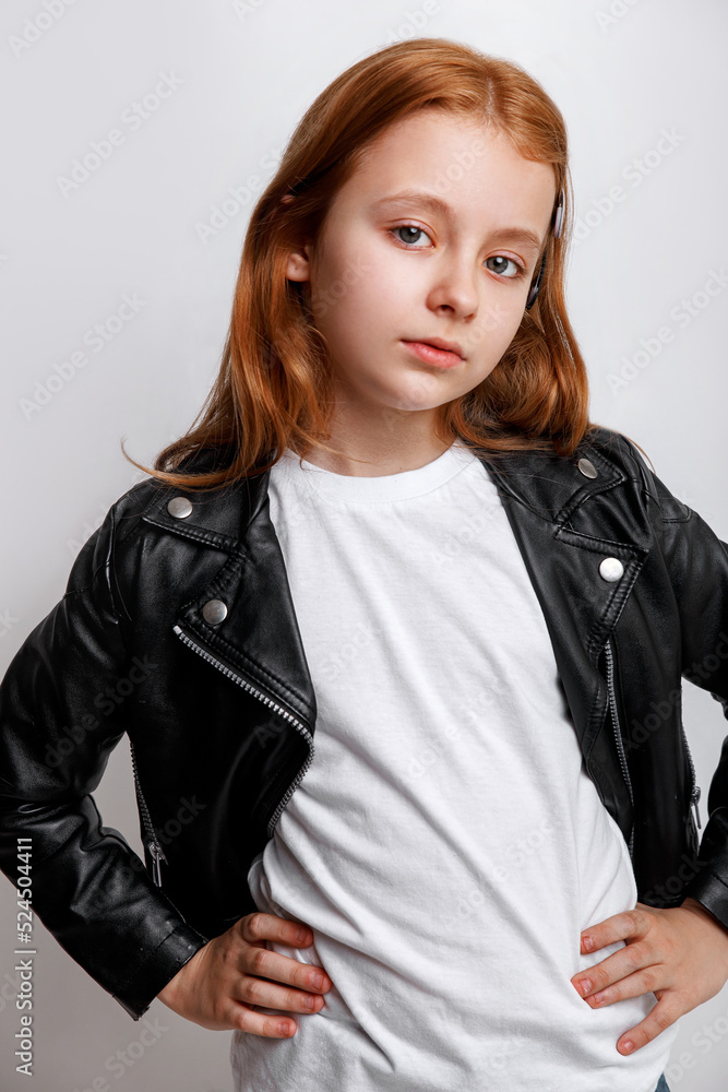 Redhead little girl model posing in white t-shirt and leather jacket on grey background Redhead little girl model posing in white t-shirt and leather jacket on grey background