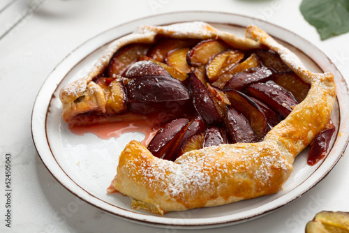 Close up of plum fruits pie galette on light plate food