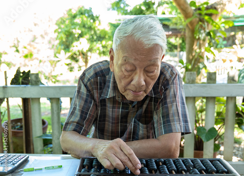 Old man using Chinese abacus, natural background photo