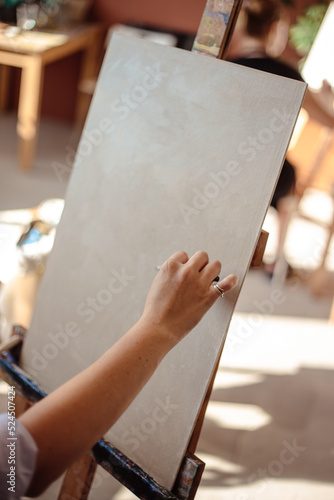 Female artist sketching a painting with a pencil on canvas