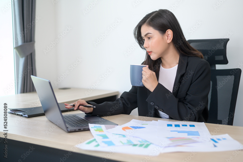 Young beautiful business woman working on laptop with documents in modern office Young beautiful business woman working on laptop with documents in modern office