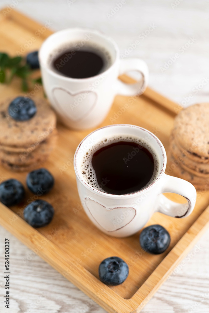 Blurred image on a tray of two cups of espresso, cookies and blueberries. Blurred image on a tray of two cups of espresso, cookies and blueberries.