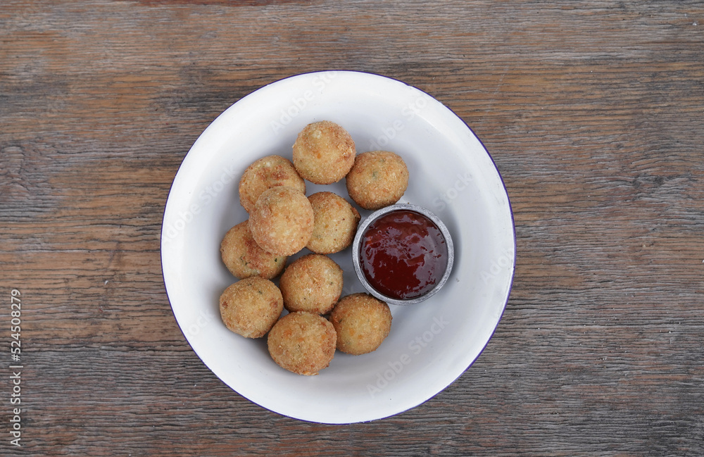 Fritters. Top view of potato and mozzarella cheese croquettes with sweet chili dipping sauce, in a white bowl on the wooden table. Fritters. Top view of potato and mozzarella cheese croquettes with sweet chili dipping sauce, in a white bowl on the wooden table.