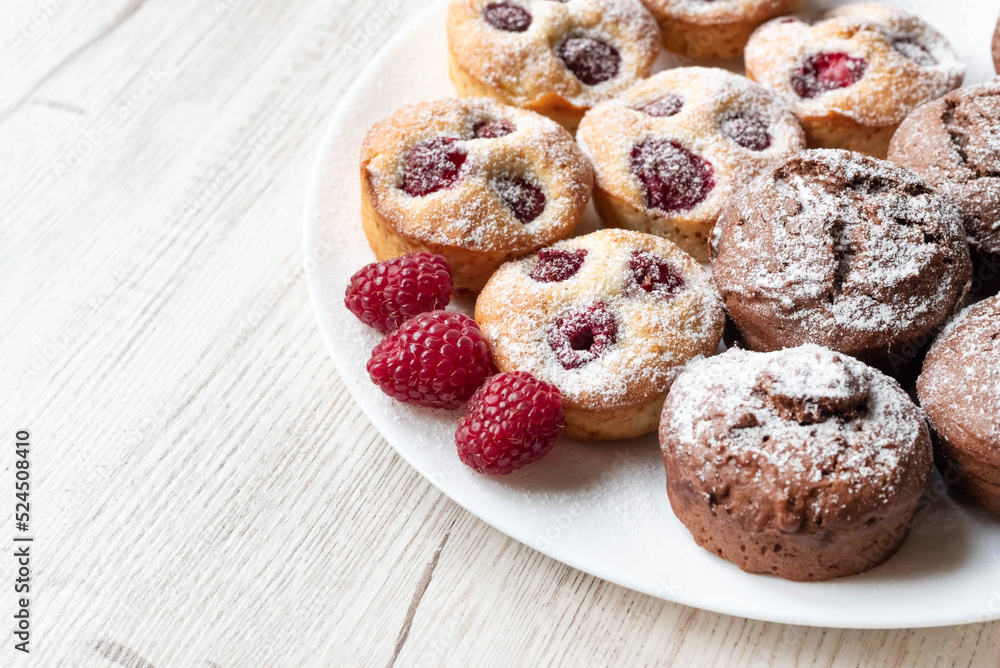 On a light table, a blurred image of raspberry and chocolate muffins. The concept of carbohydrate products.