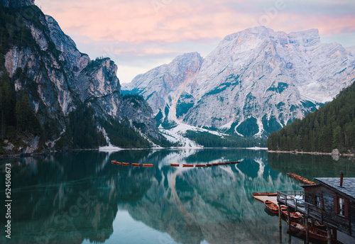 Stunning view of the Lake Braies (Lago di Braies) with some wooden boats and beautiful mountains reflected in the water. Lago di Braies is an alpine lake in the Dolomites, Italy