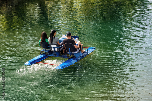People having rest, tanning, swimming, using a catamaran on a lake in summer.