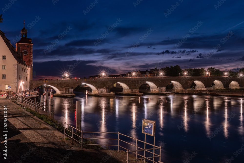 Steinerne Brücke nachts beleuchtet mit Spiegelung in Regensburg