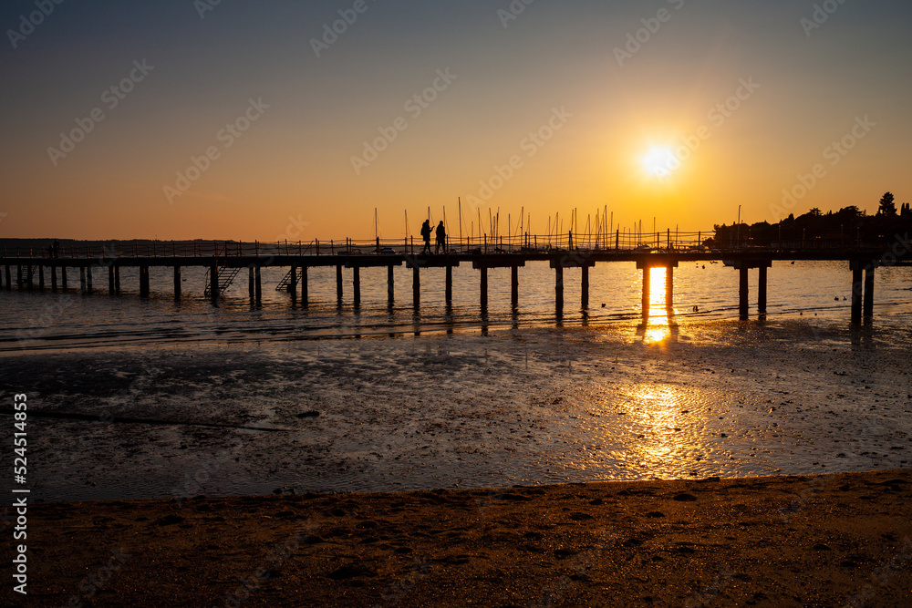 High quality photo of a pier at sundown. Wooded bridge seaside with Sunset, Strunjan. Slovenia