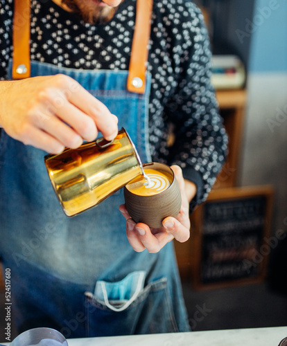 Un barista haciendo arte latte en un flat white