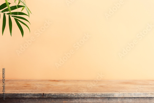 wooden table in front of interior wall and tropical green plant background. for product display and presentation.