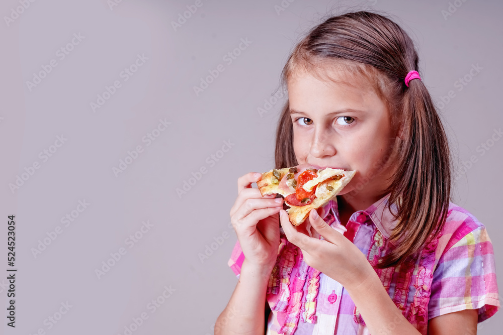 Kids' pizza. Portrait of happy young beautiful child girl bites slice of pizza. Copy space. Kids' pizza. Portrait of happy young beautiful child girl bites slice of pizza. Copy space.