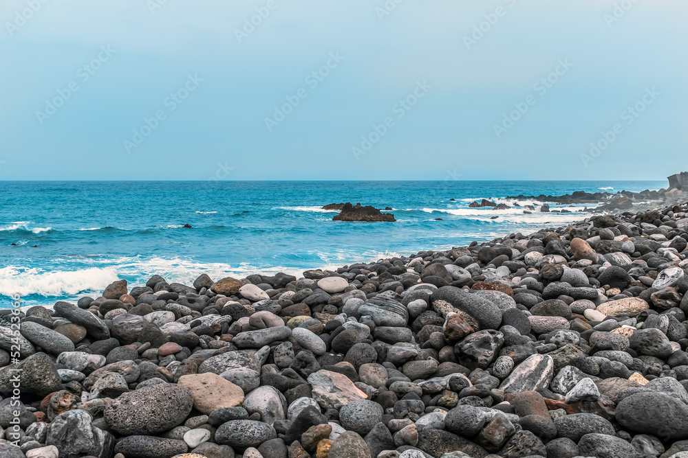 Black and brown volcanic stones on the shore of the Atlantic ocean in Puerto de la Cruz in the Canary Islands, Spain. Seascape in Tenerife