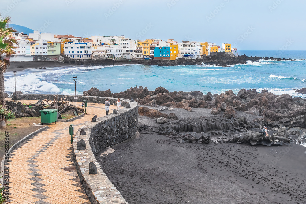 Puerto de la Cruz, Spain - November 25, 2021: Promenade in Puerto de la Cruz. Atlantic Ocean coastline and empty Playa Chica beach with black sand during a storm