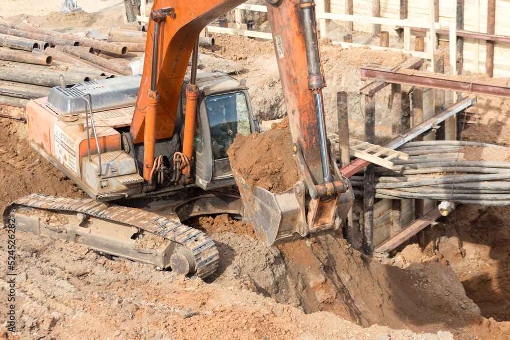 Fototapeta premium The excavator is working on a city construction site. Repair and construction concept.