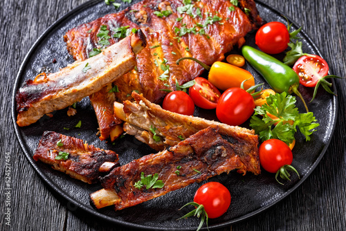 Billede på lærred BBQ Ribs with tomatoes and chili on  black plate
