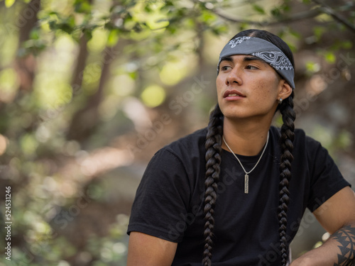 Close-up side profile image of an Indigenous man in a forest 